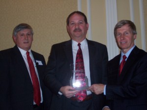 NH Department of Resources & Economic Development Commissioner George Bald (l.) and Governor John Lynch (r.) congratulate Sig Sauer Counsel Steve Shawver on Sig's designation as "Commissioner's Company of the Year."