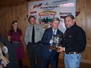 Outgoing Laconia Motorcycle Week Association Board President Paul Lessard receives the Fritzie Baer Award for his dedication to Motorcycle Week from Governor John Lynch as Jennifer Anderson and Charlie St. Clair of the Motorcycle Week Association look on.